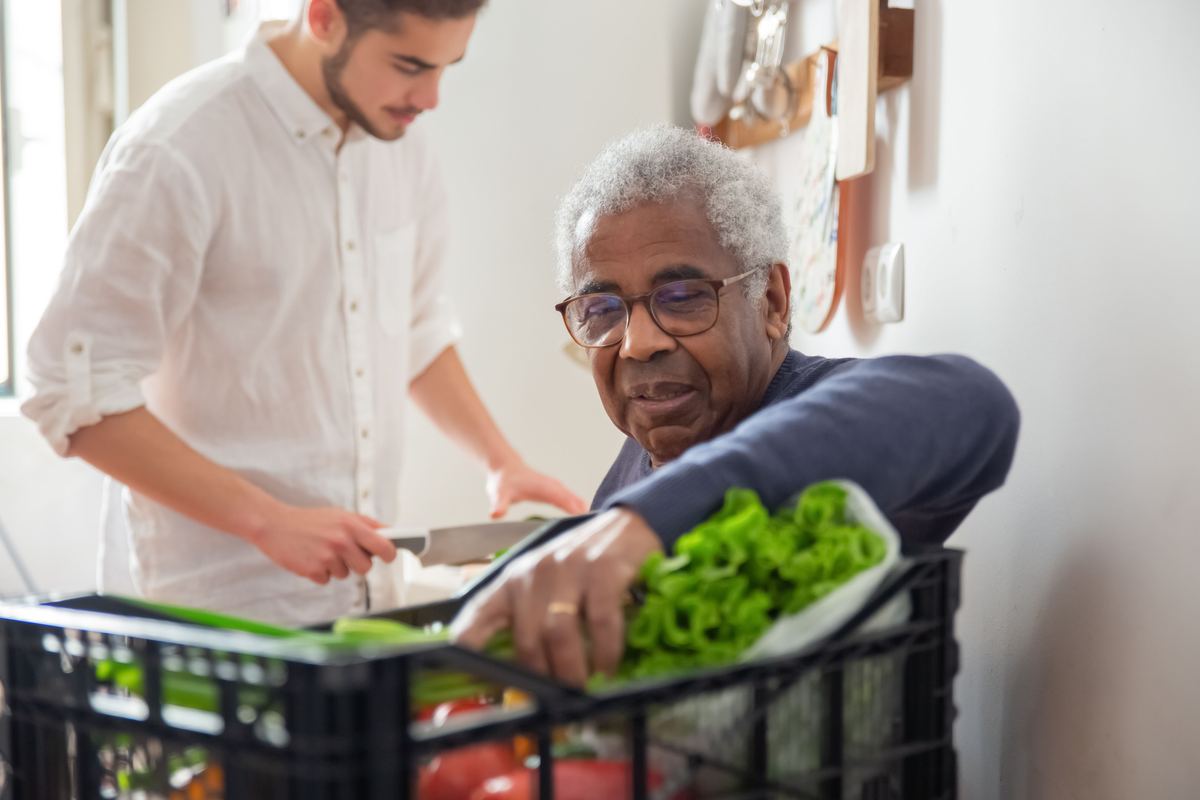 Support worker and participant preparing fresh vegetables together in the kitchen