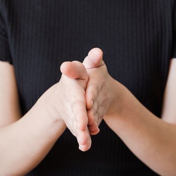 Hands gently clasped together in a calm, attentive gesture